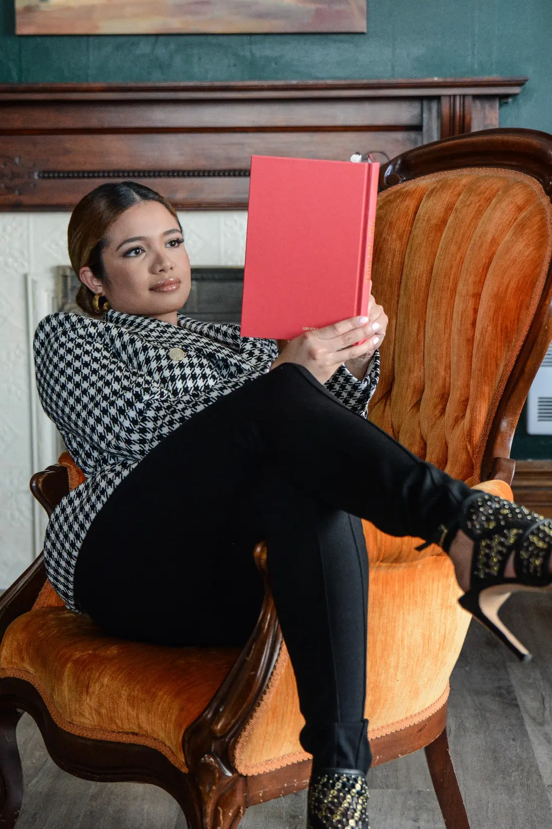 Eve reading in a velvet armchair beside a fireplace